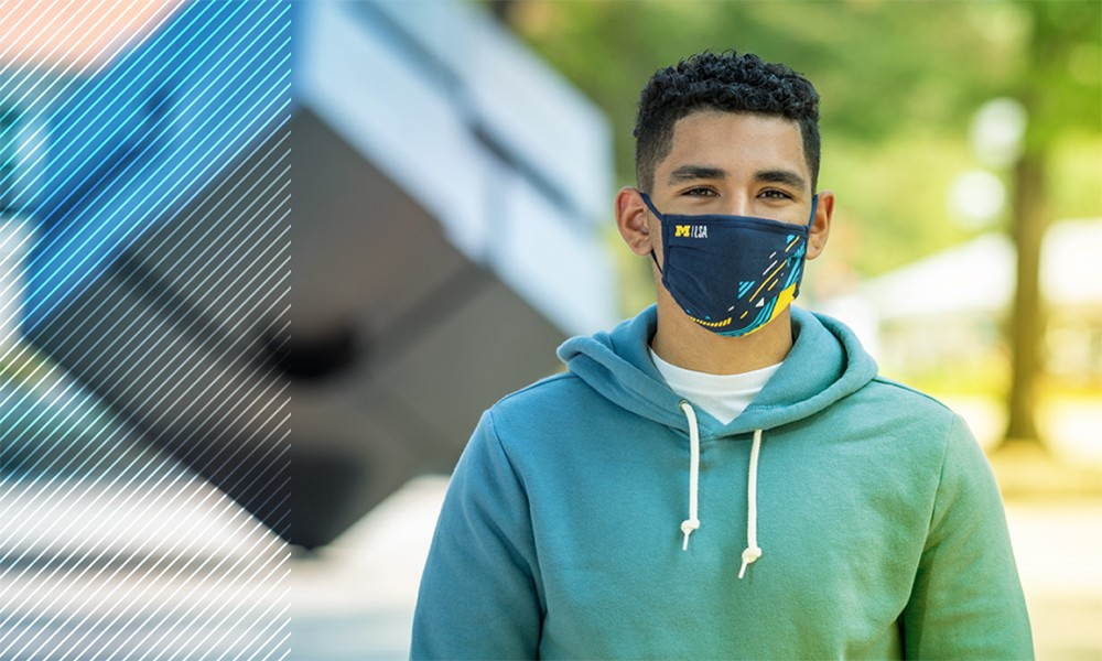 U-M student J.J. wearing a mask, standing in front of the LSA Cube.