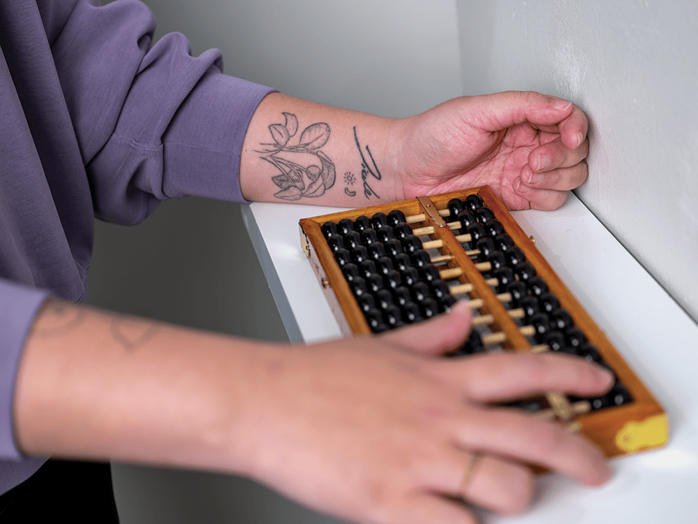 A photograph of Lily Jiale Chen’s hands, framing a wooden abacus.