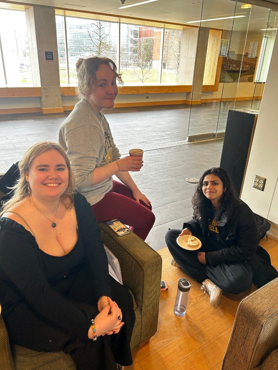 Three students are pictured having tea in a lounge at Alice Lloyd Hall. They are all smiling at the camera.
