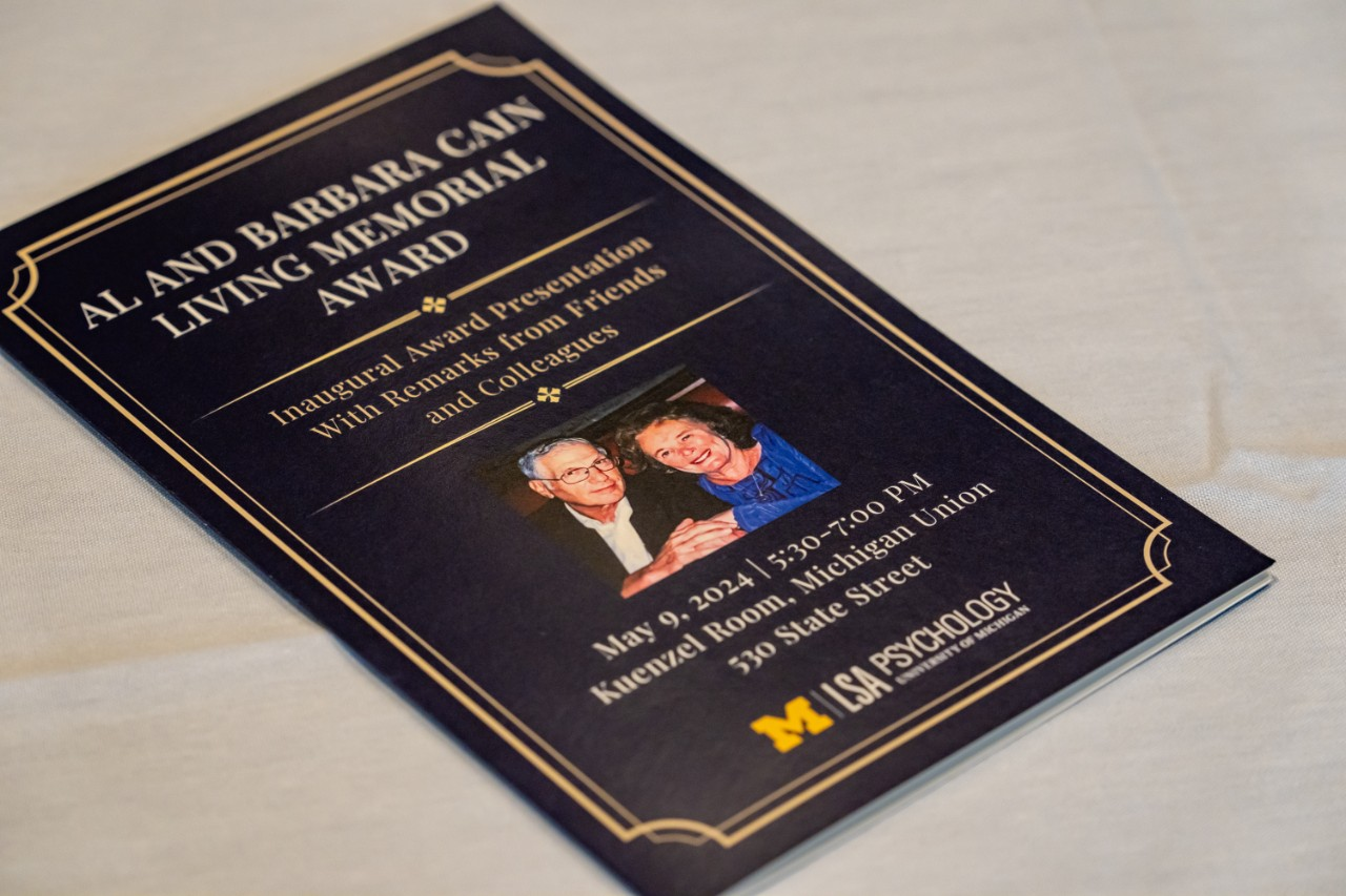 The cover of the program for the Al and Barbara Cain Memorial Award Inaugural Award Presentation. The program is navy blue with gold lettering and border and features a photo of Al and Barbara Cain together. The program also states, With Remarks from Friends and Colleagues, as well as the date, time, and location of the event, May 19, 2024, 5:30-7:00 PM, in the Kuenzel Room at the Michigan Union., 530 S. State St.