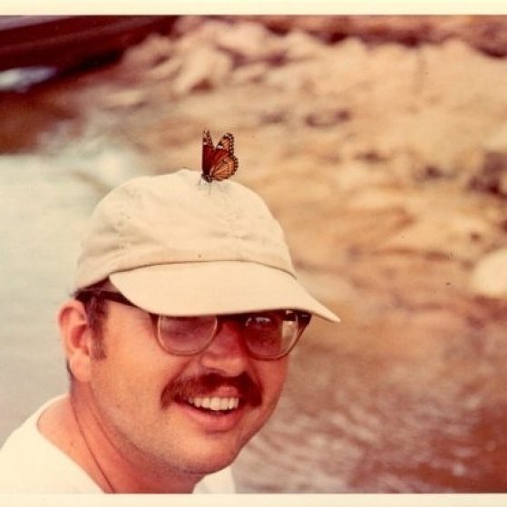 Dr. Neal Foster poses with a Viceroy butterfly, a species that mimics the color pattern of Monarch butterfly. The butterfly is perched on the top of Foster's baseball cap, drinking sweat from the fabric to get certain salts.