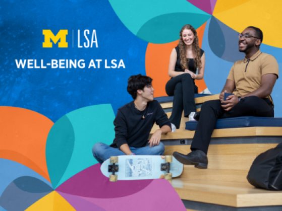 Student  Mental Health and Well-Being Student Advocate Brandon Bond sits with three students on the stepped benches in the LSA Building Atrium. Bond is wearing black framed glasses, black pants, black boots, and a tan short-sleeved polo shirt with black tipping at the collar and placket. Everyone in the group is smiling and turned toward one another, it appears they are engaged in animated conversation. The students are dressed casually in jeans. One student has a skateboard, and one has a backpack. There multi-colored LSA Wellness Wheel, which resembles a garden pinwheel, is overlayed onto the photo stylistically.