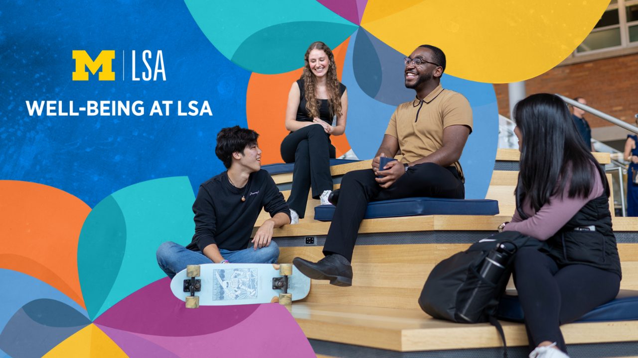 Student  Mental Health and Well-Being Student Advocate Brandon Bond sits with three students on the stepped benches in the LSA Building Atrium. Bond is wearing black framed glasses, black pants, black boots, and a tan short-sleeved polo shirt with black tipping at the collar and placket. Everyone in the group is smiling and turned toward one another, it appears they are engaged in animated conversation. The students are dressed casually in jeans. One student has a skateboard, and one has a backpack. There multi-colored LSA Wellness Wheel, which resembles a garden pinwheel, is overlayed onto the photo stylistically.