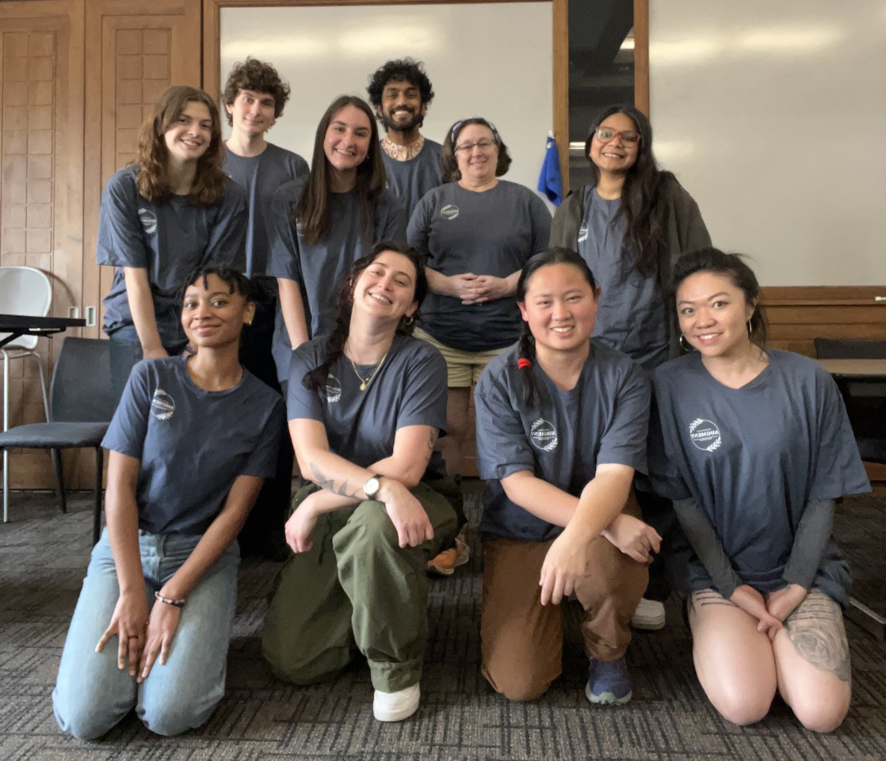 Ten AUGMENT students pose for a group photo in a Union meeting room. They wear matching dark grey t-shirts with the AUGMENT logo.