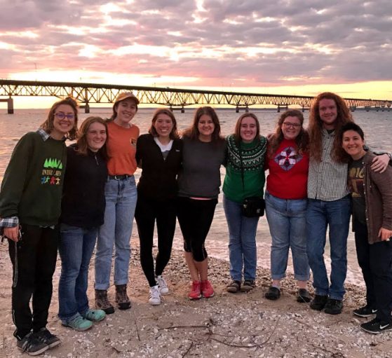 Class standing with the Mackinac Bridge and colorful sunset in the background