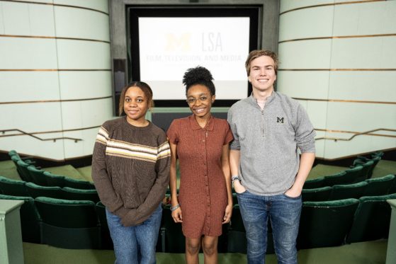 Three students standing as a group and smiling. 