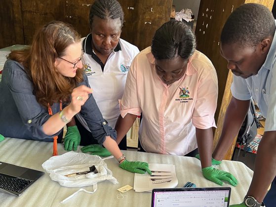 A group of people examining a small object on a table.