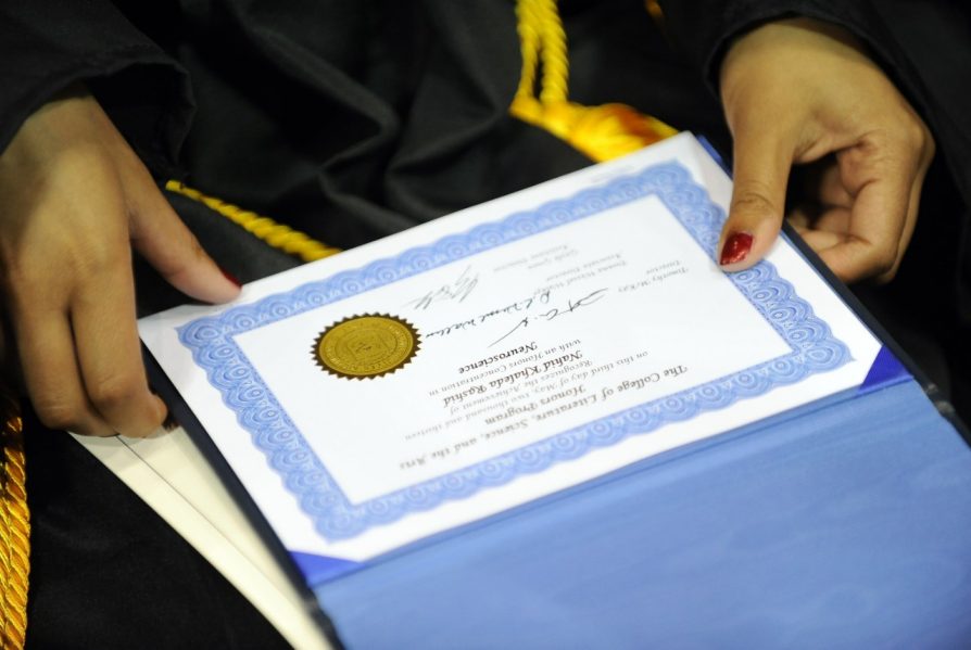 Graduate holding their Honors certificate