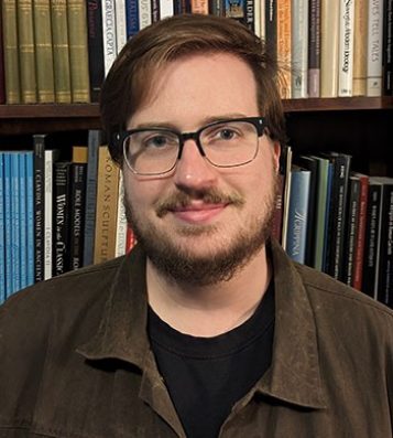 IPAMAA student Andrew Crocker standing in front of bookcase