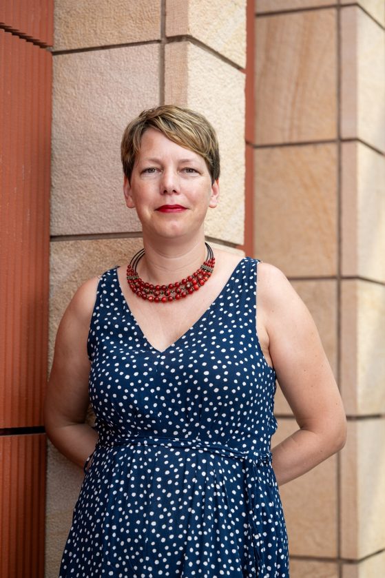 Professional headshot of Dr. Anna Hajkova standing in front of white building. 