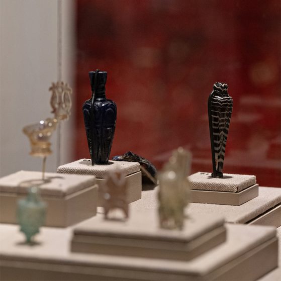 Display case in the Kelsey Museum showing a small assemblage of Islamic flasks made of turquoise, pink, clear, and black glass.