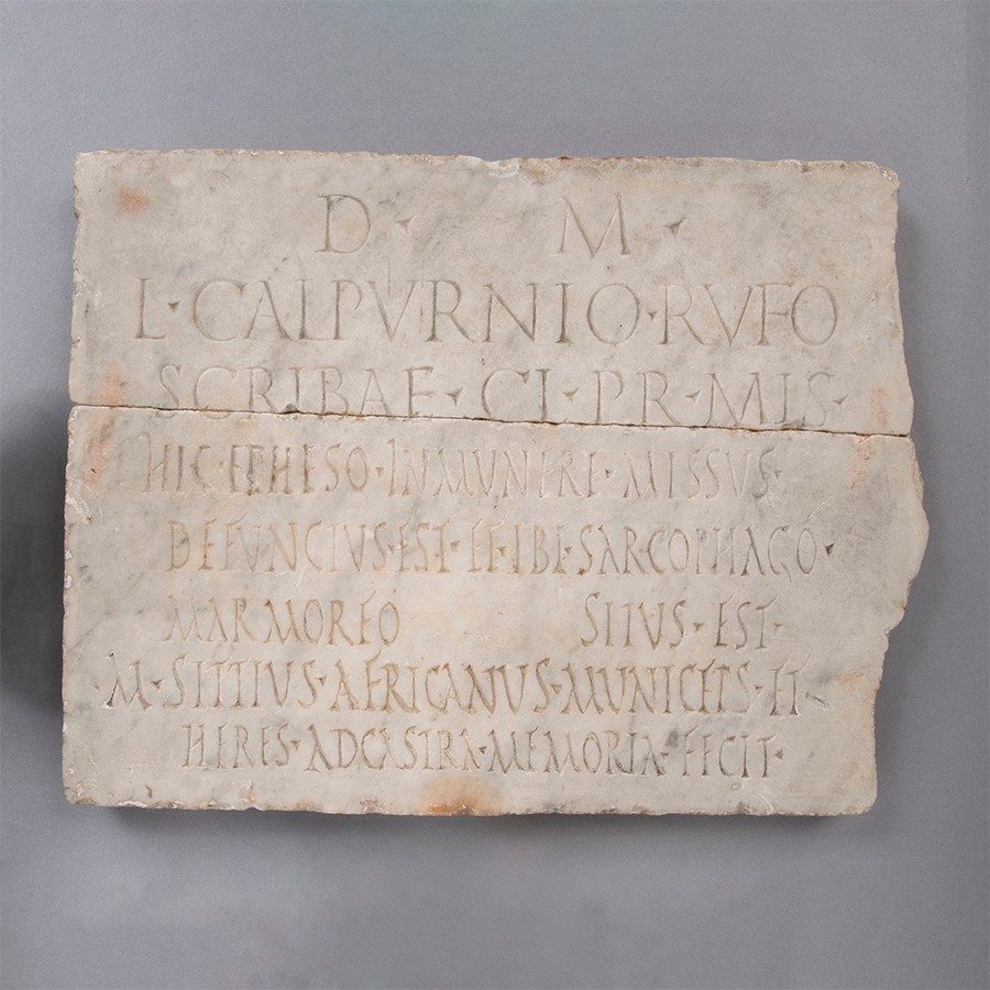 Roughly rectangular piece of white marble with eight rows of Latin inscription.