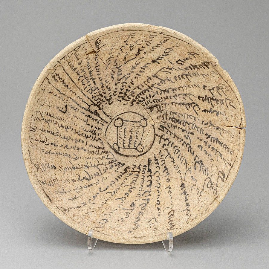 Light tan bowl with inscriptions radiating out from the center in black ink.
