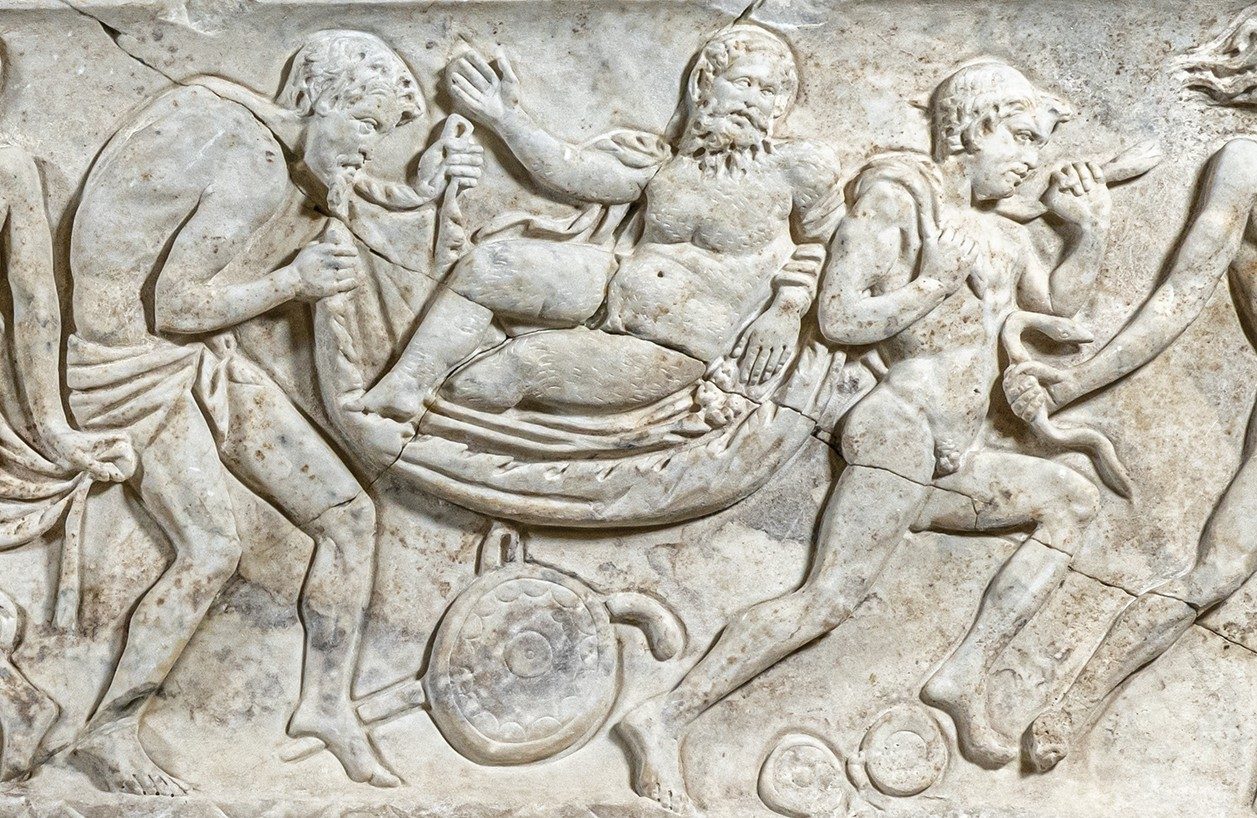 Close-up of a section of a while marble sarcophagus showing the god Dionysus being carried in a procession.