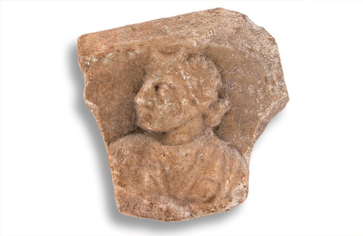 Fragment of tan marble showing a bust of the goddess Caelestis in profile.