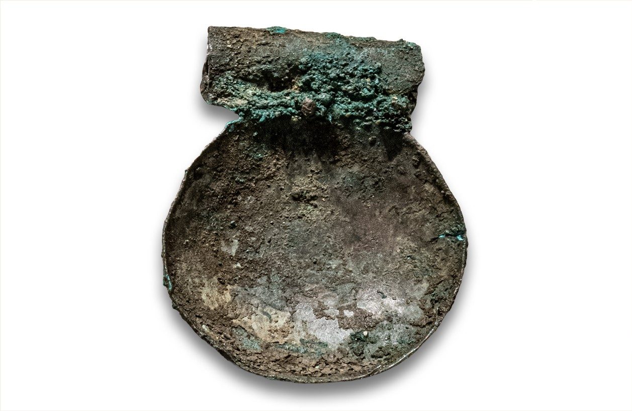 A small, corroded bronze pendant.