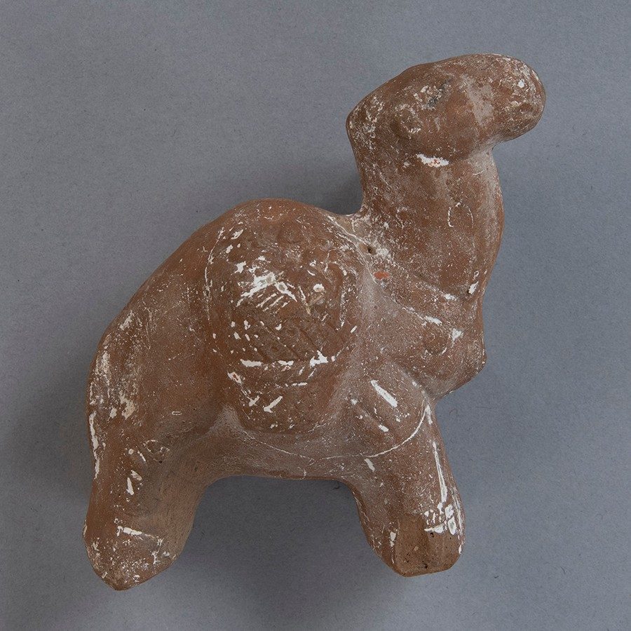 The head and body of a camel made out of dark brown clay.