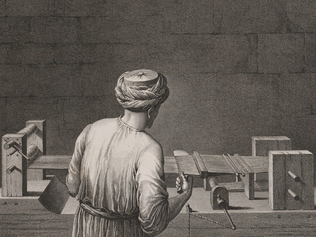 Illustration showing the back of a man as he operates a small, horizontal loom. He wears a robe, a turtur, and a turban.