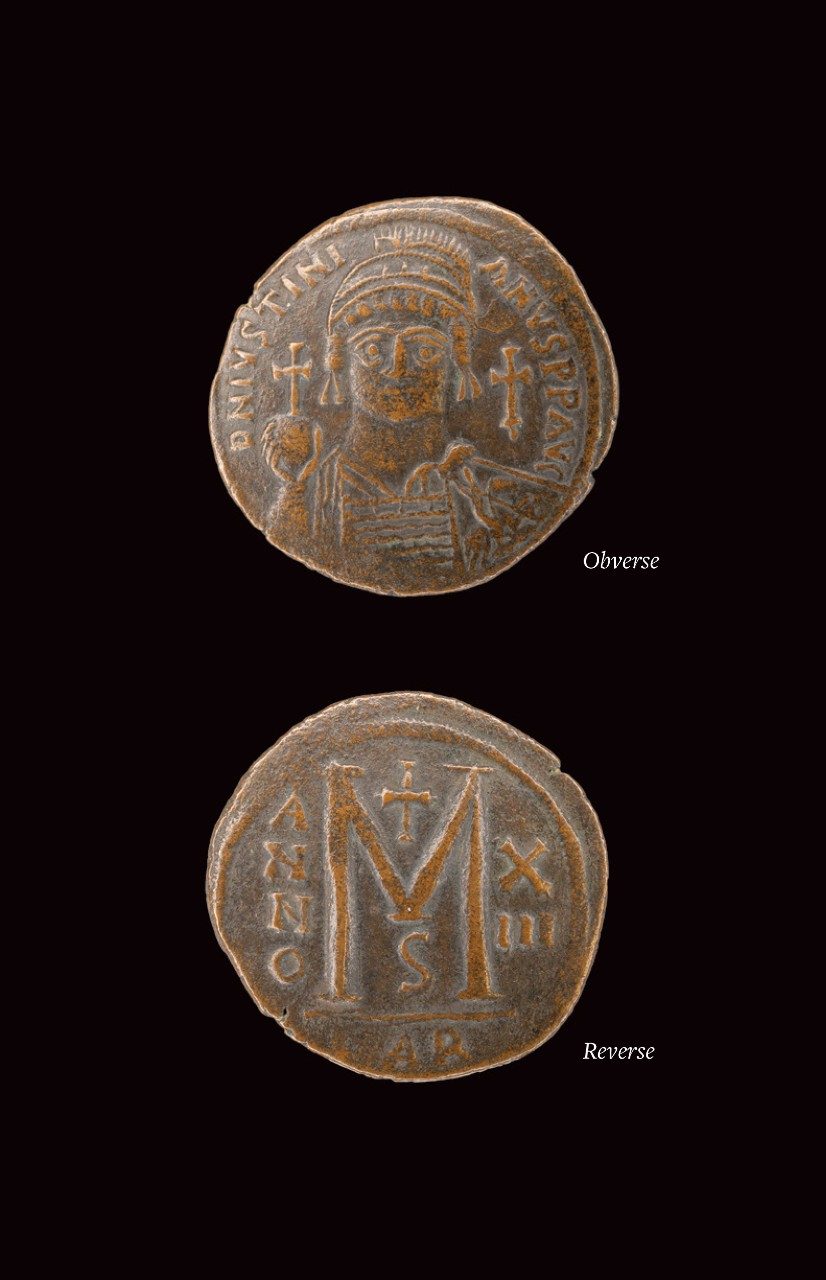 Collage of the front and back views of a bronze coin; the left shows a bust of a man wearing a diadem and holding a cross with a line of inscription surrounding him, and the right has a large M topped by a cross, surrounded by a date.