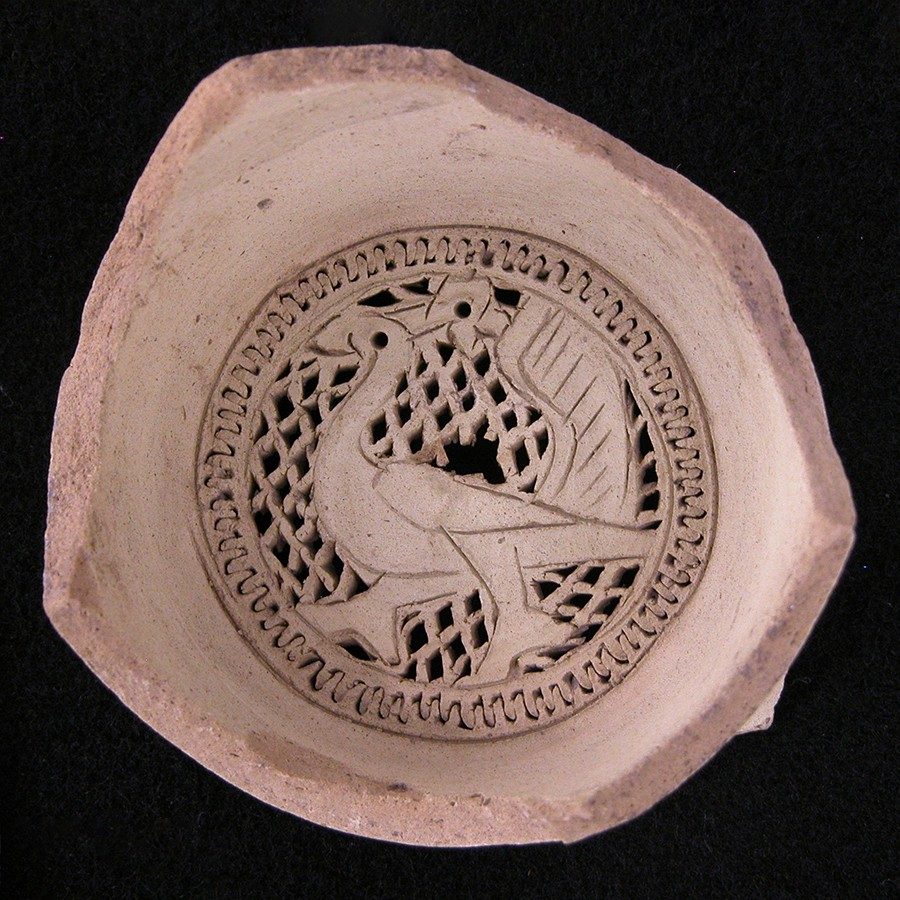 Buff-colored clay water filter with a design of a plumed bird walking at the bottom.