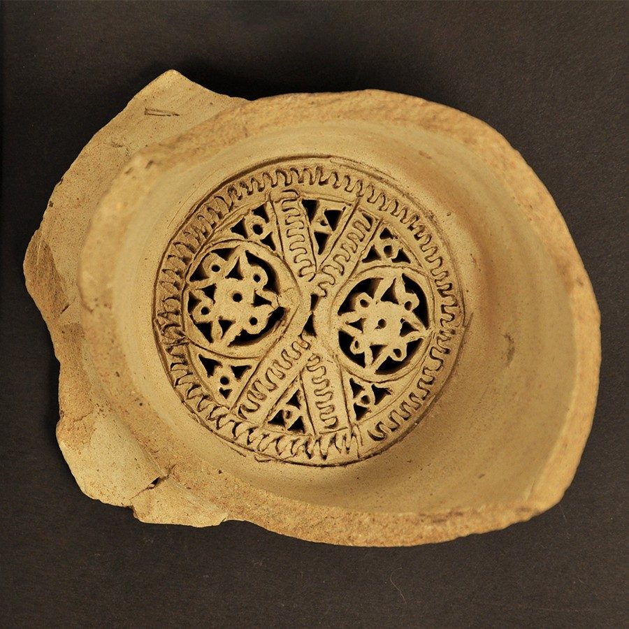 : Buff-colored clay water filter with geometric shapes radiating out from the center.