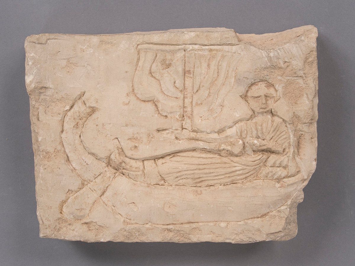 Limestone slab carved with the image of a man reclined in a sailing vessel.