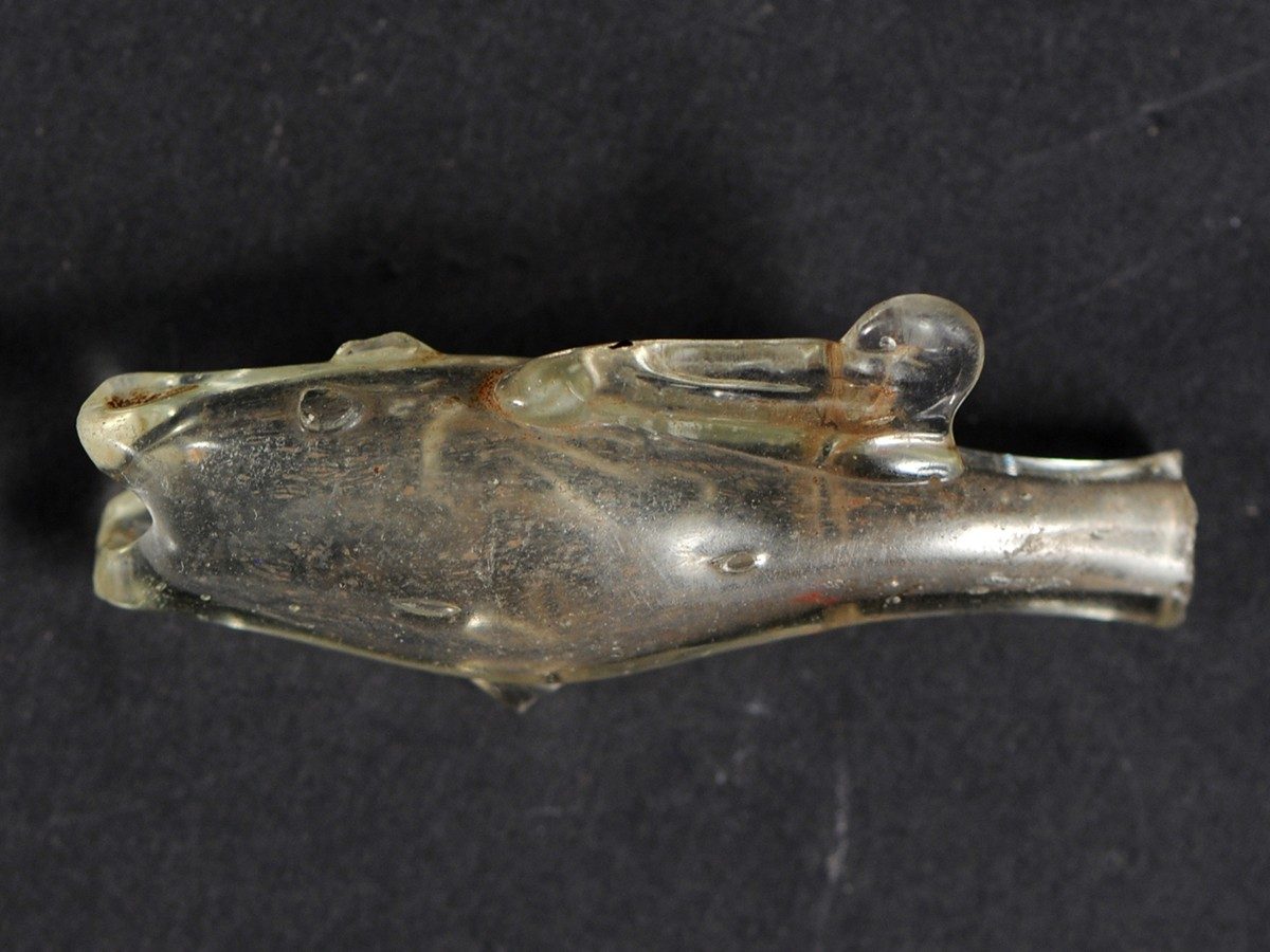 Small vessel made of clear glass, shaped to resemble a fish. 