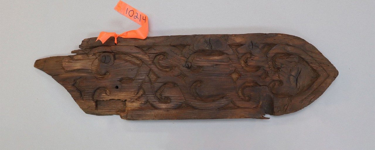 Roughly rectangular wooden relief panel with carved pattern of intertwined vines.