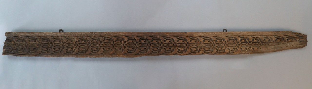 Long, rectangular wooden relief panel with interlacing pattern. 