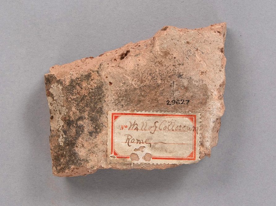 Roughly rectangular ceramic brick. On its surface is a sticker reading “Hall of Colosseum, Rome.”