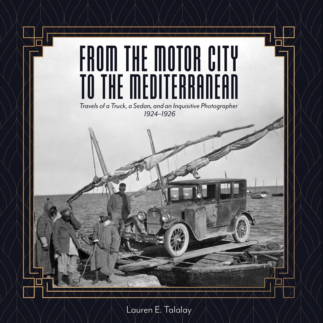Cover of “From the Motor City to the Mediterranean: Travels of a Truck, a Sedan, and an Inquisitive Photographer, 1924–1926.” An art deco–style frame encloses an archival photo showing a 1920s sedan loaded atop a makeshift ferry consisting of fishing boats connected by ropes and planks. To the left stands a worker from the University of Michigan expedition and three Tunisian men.