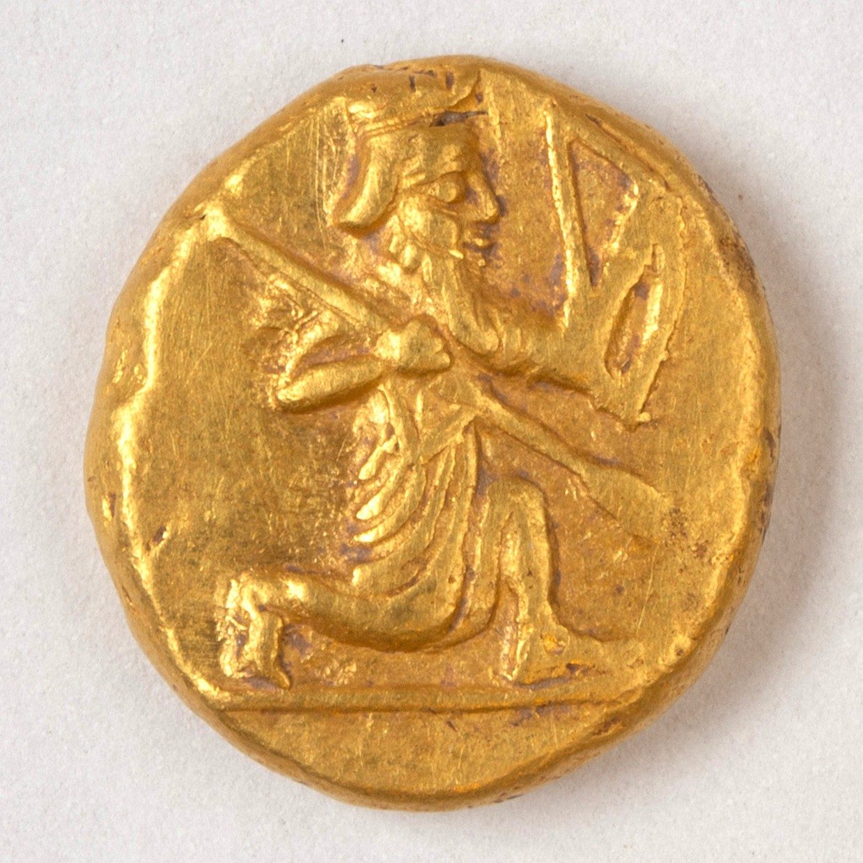 Gold coin featuring a kneeling man with weapons.