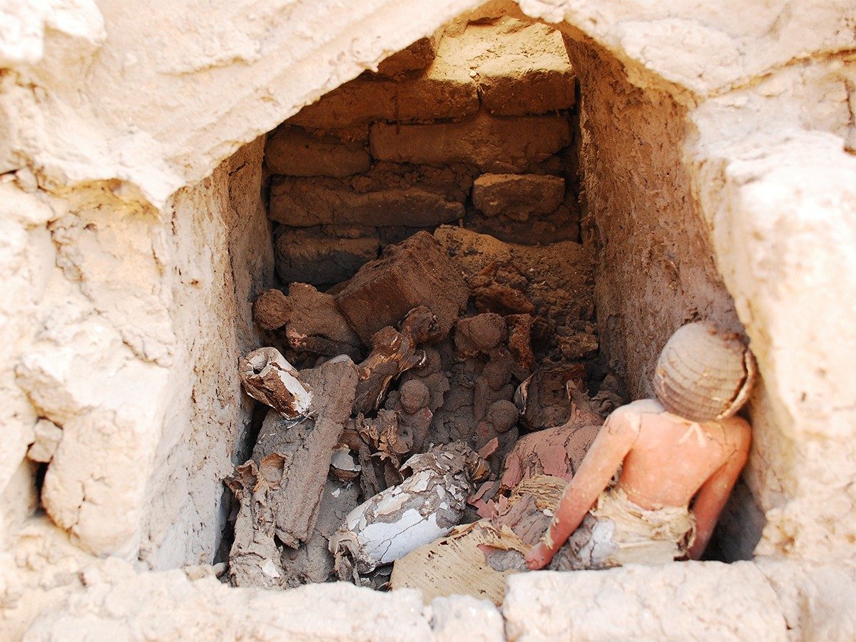 View into a small stone chamber filled with crumbled wooden statues.