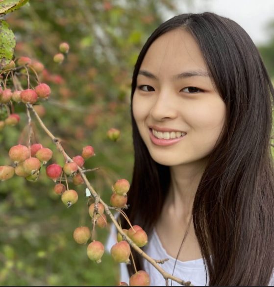 Woman with dark hair smiles against outdoor background
