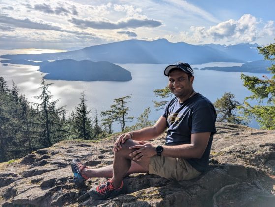 Student sitting on rock in front of water