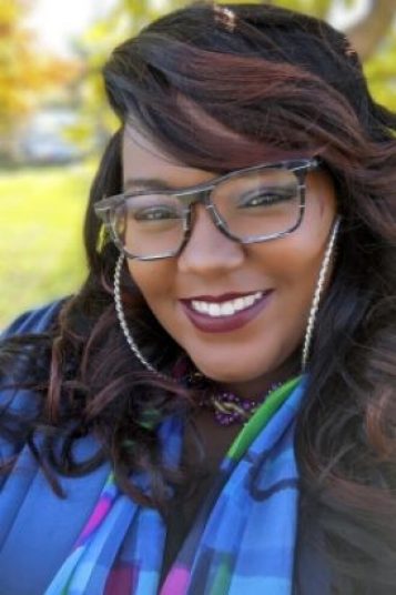 portrait of Ari Kozik, Black woman with long hair wearing glasses, smiling