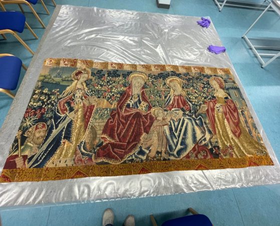 A textile laying a plastic sheet with a blue floor in the background