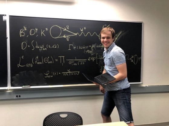 Marius Kongsoere posing in front of a chalkboard with equations on it