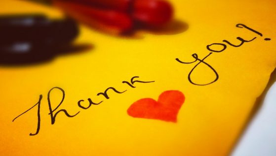 A handwritten note on yellow paper that says "Thank you!" with a red heart drawn below the text.