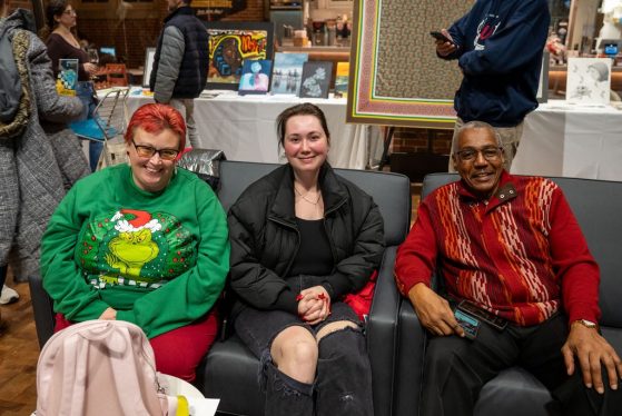 Group of three people sitting in chairs, smiling for photo
