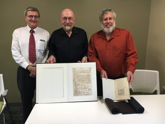 Nobel Prize recipient Kip S. Thorne, Professors of Physics Keith Riles, and Gregory Tarlé at the Special Collections Library in Hatcher Graduate Library. Professor Kip Thorne is holding the original document