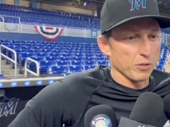 a man with a Marlin's baseball cap in a black t-shirt being interviewed by reporters.