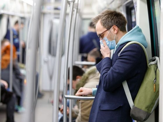 Ill man in glasses feeling sick, coughing, wearing protective mask against transmissible infectious diseases and as protection against the flu in public transport. New coronavirus 2019-nCoV from China