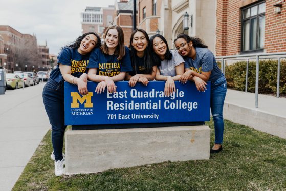 four students behind Residential College signage