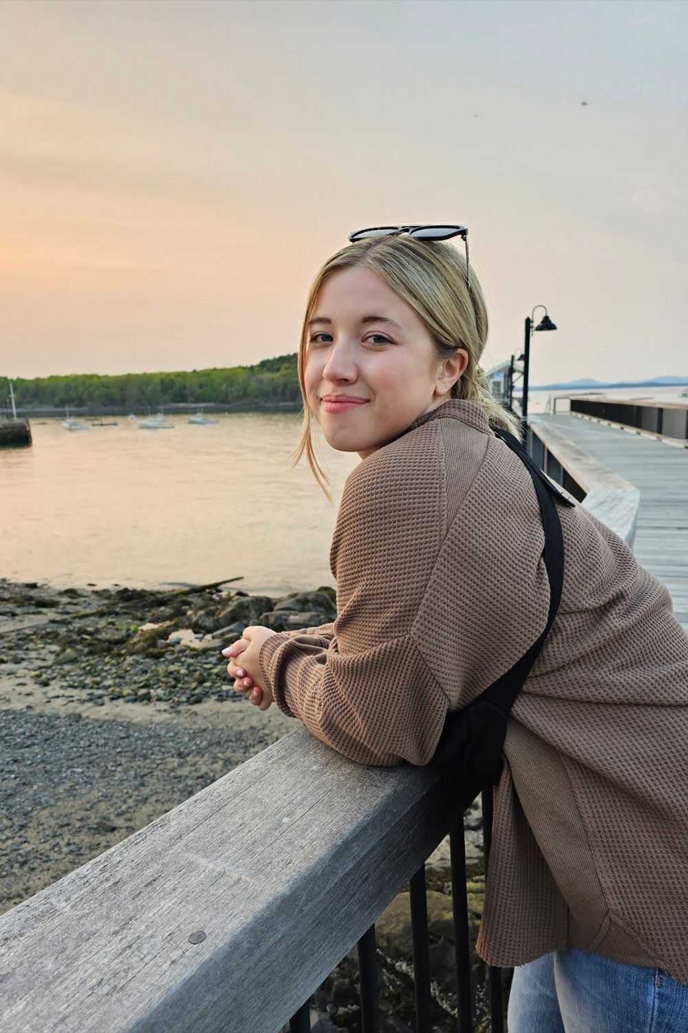 Katie Penrod stands on a wooden dock on a beach at sunrise