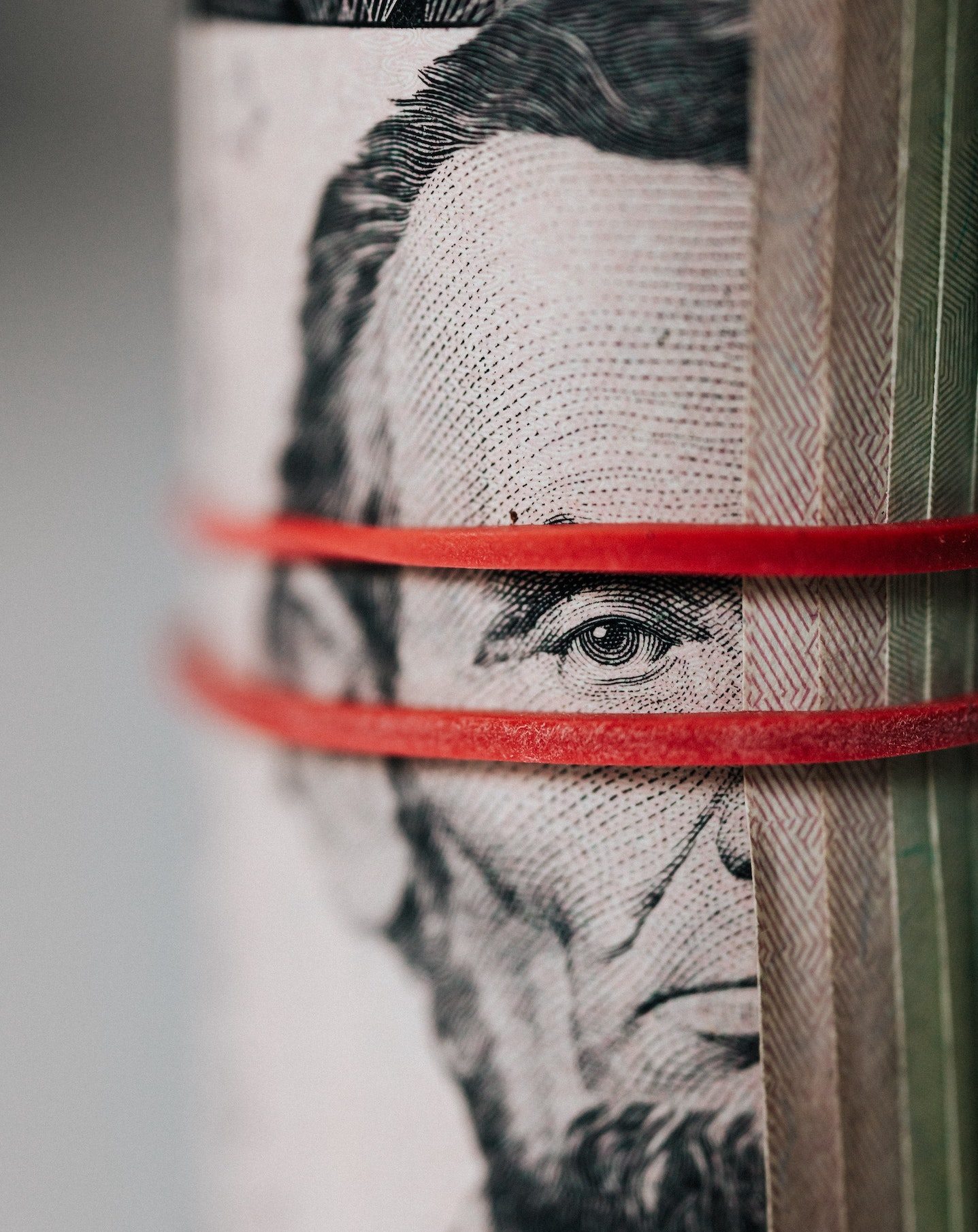 Closeup of rolled United States five dollar bills tightened with red rubber band