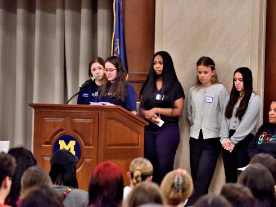 A student speaks at a podium to a crowd