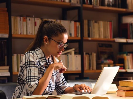 Young female student study in the library using laptop for researching online.