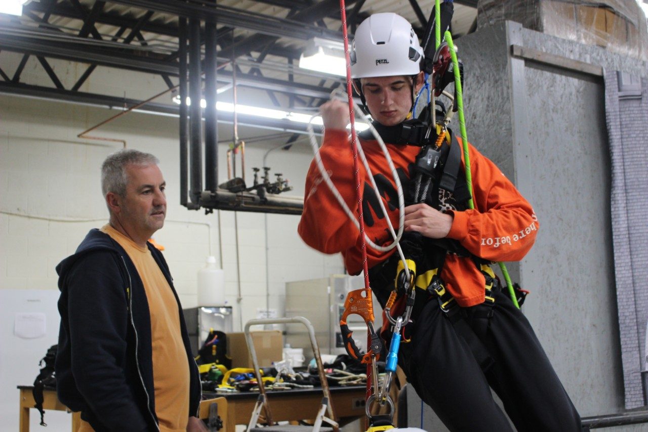 Person hanging from a harness inside a building