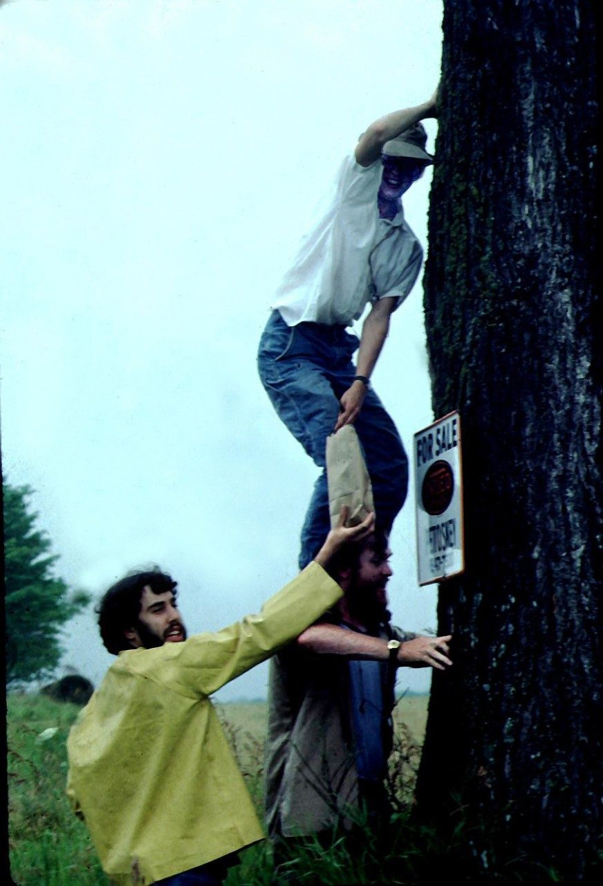 Woman standing on someone's shoulders and leaning against a tree